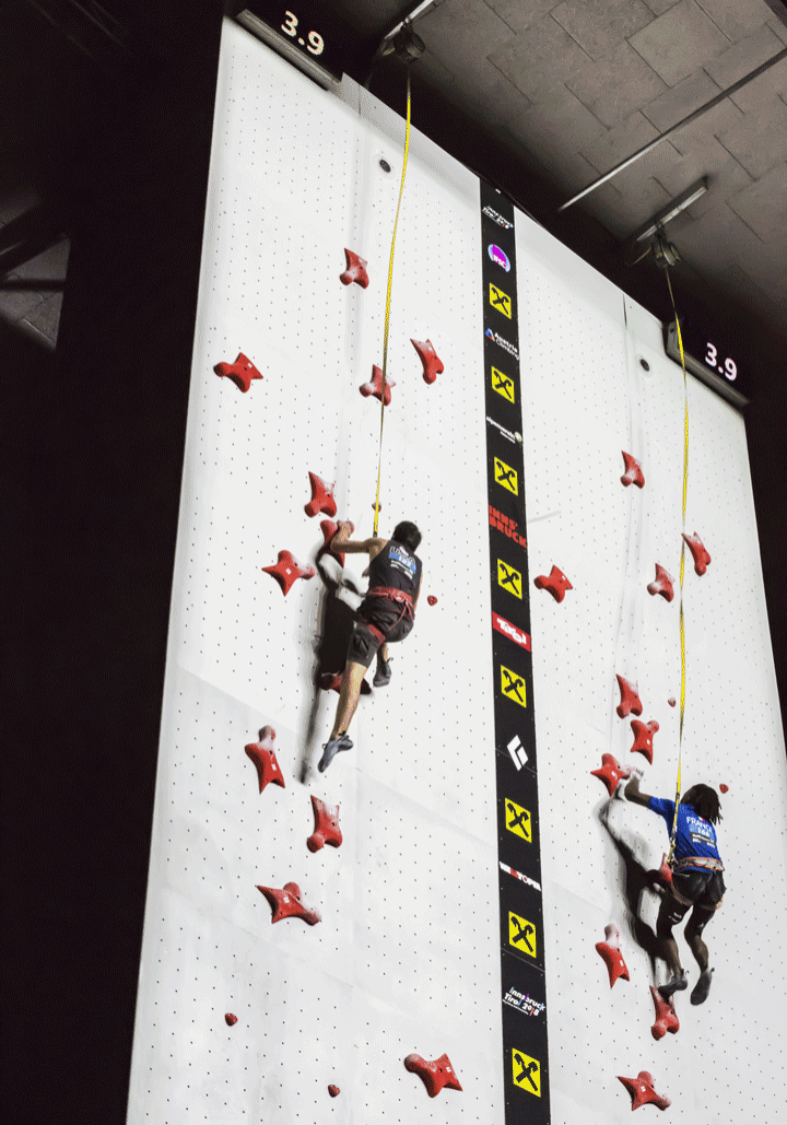 Speed climbers racing side by side up a speed climbing wall at the 2018 world climbing championship