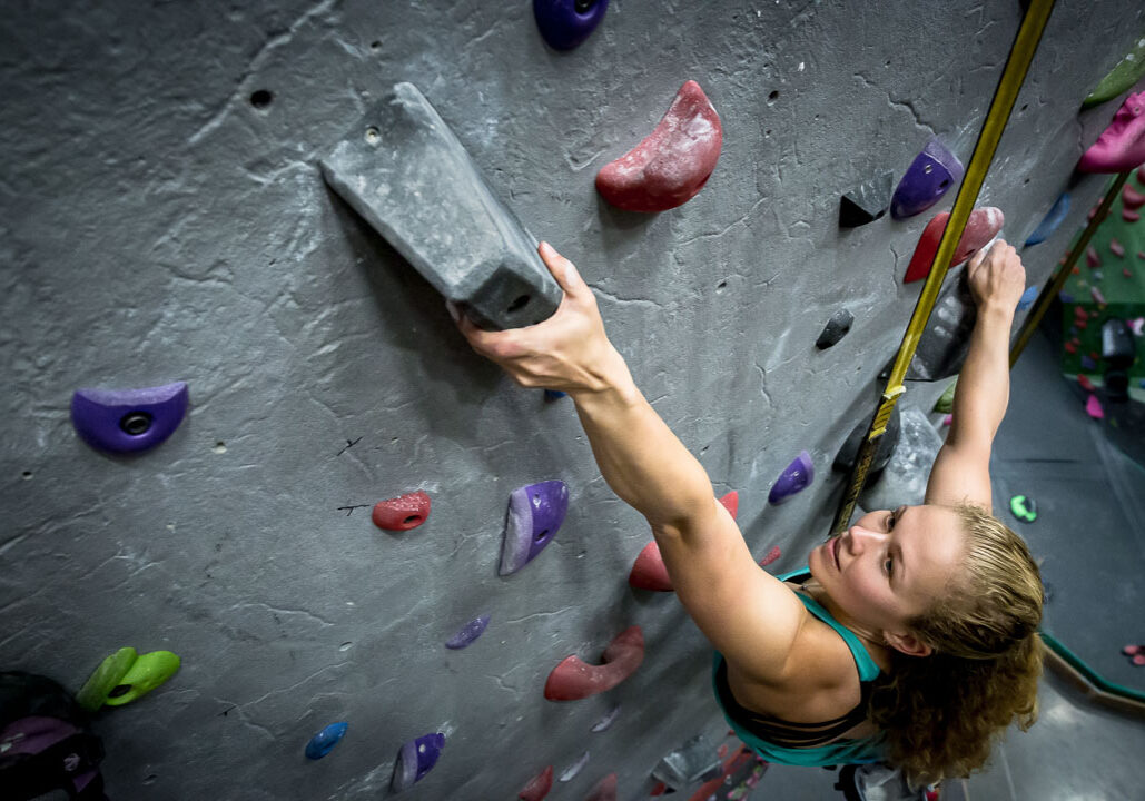 woman rock climbing in a gym on a perfect descent auto belay